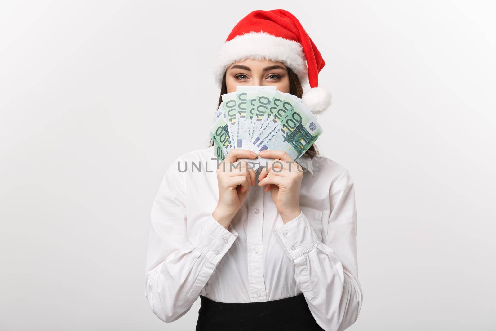 Christmas and finance concept - Young business woman showing money closing her face with surprise expression.