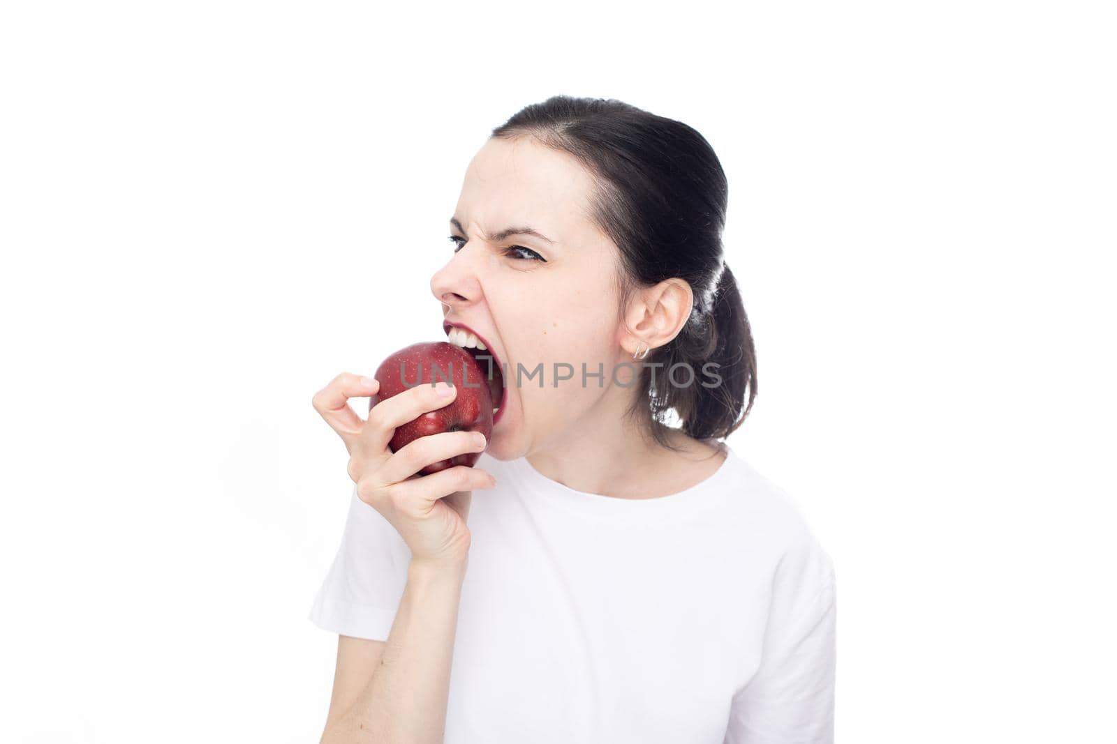 woman in white t-shirt eating red apple, white studio background. High quality photo