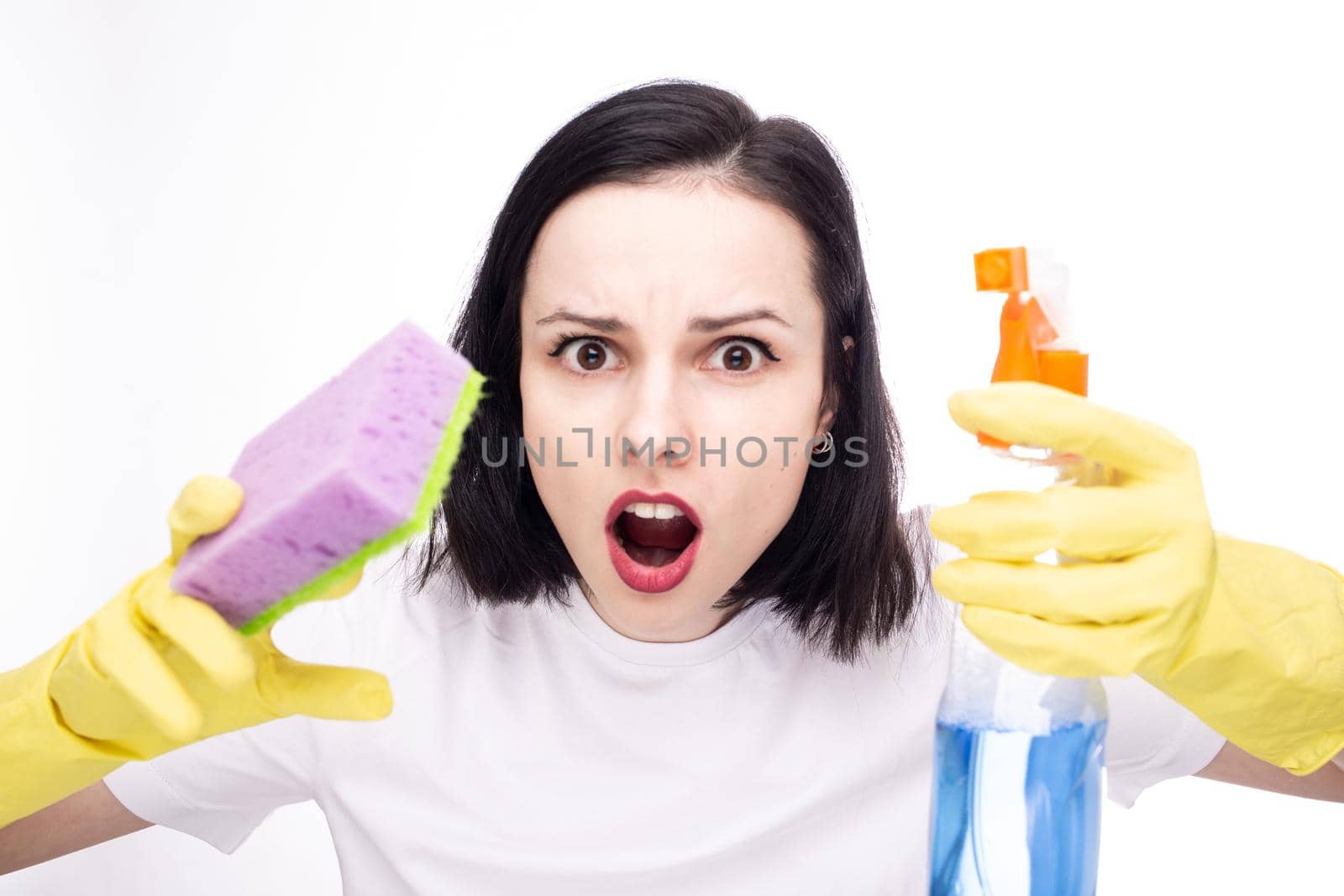 surprised woman in yellow gloves cleans, in her hands a detergent and a sponge. High quality photo