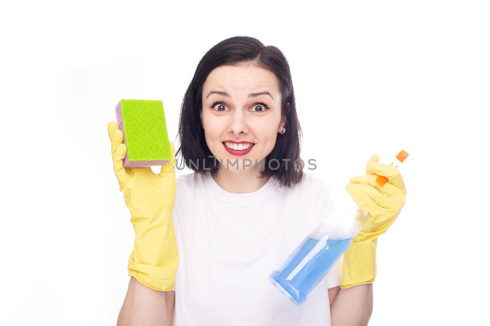 happy woman in cleaning gloves holding dishwashing sponge and household chemicals, white studio background. High quality photo