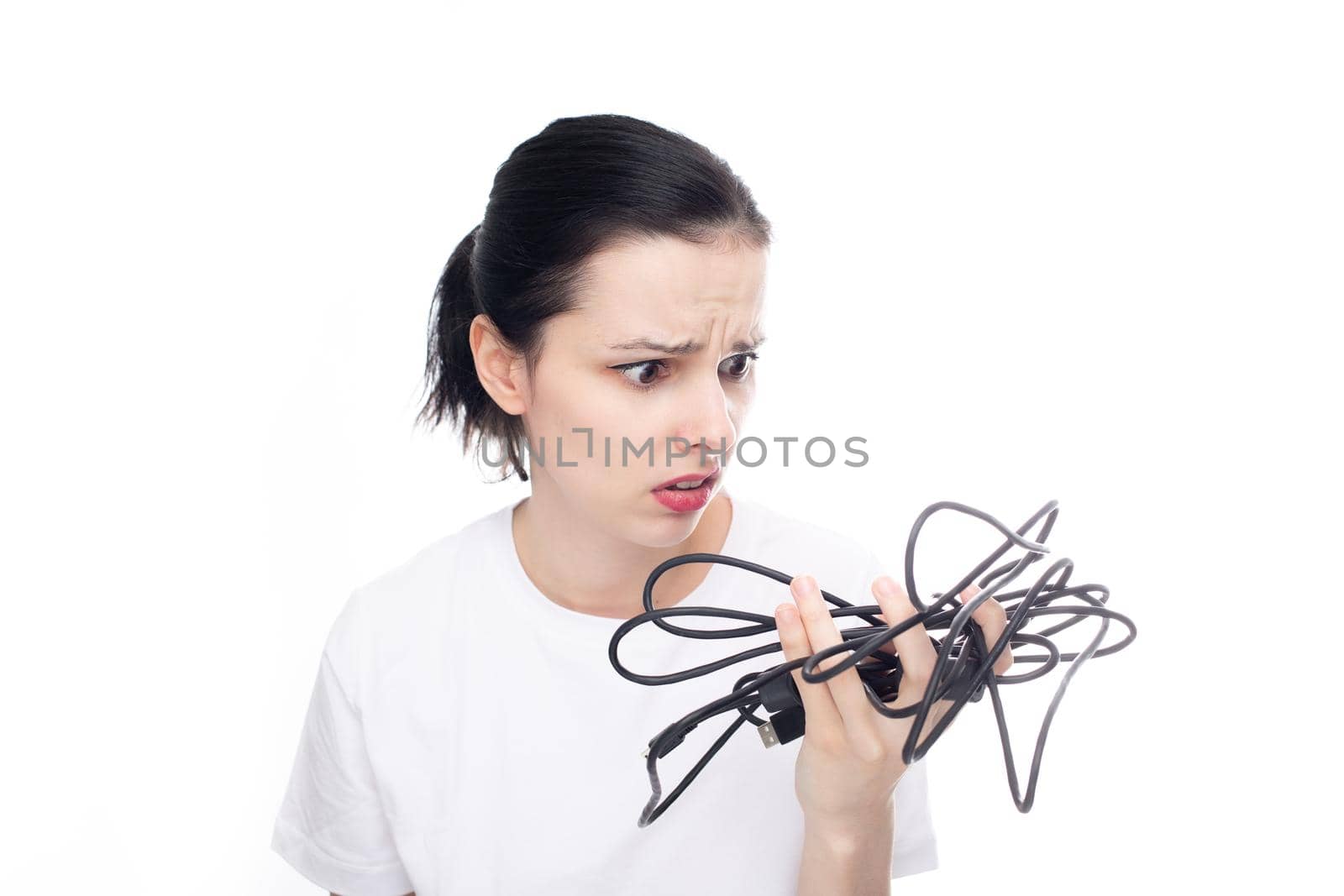 upset woman in a white t-shirt holding a wire in her hand, white background. High quality photo