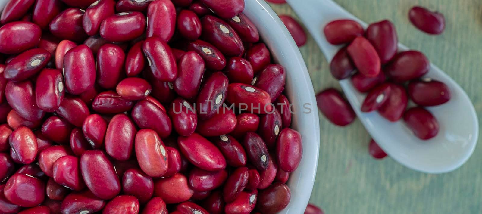 banner with close-up of red beans in a white cup with spoon on a wooden table. by Leoschka