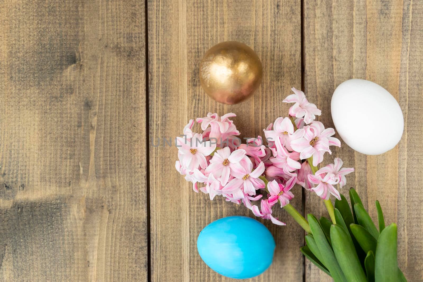 blue, white and golden eggs and pink hyacinth flowers on wooden table. Happy Easter concept. Easter background by Leoschka