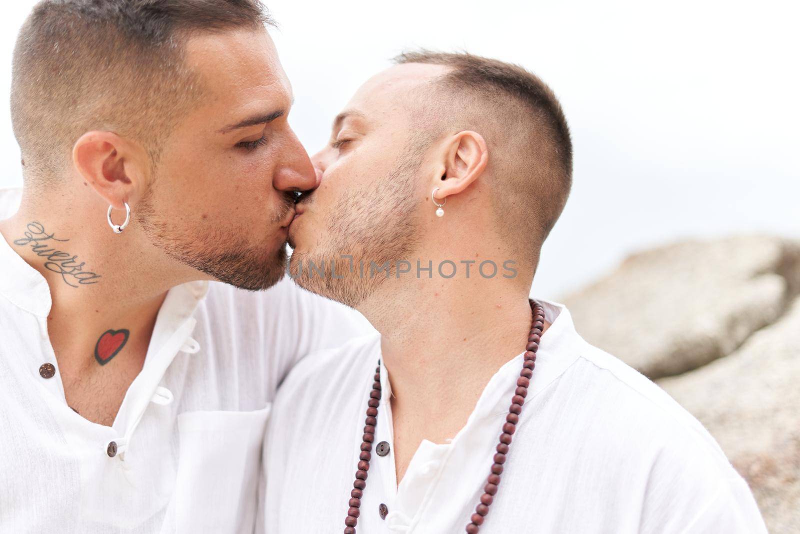 Close up portrait of an homosexual couple kissing tenderly on a topical beach