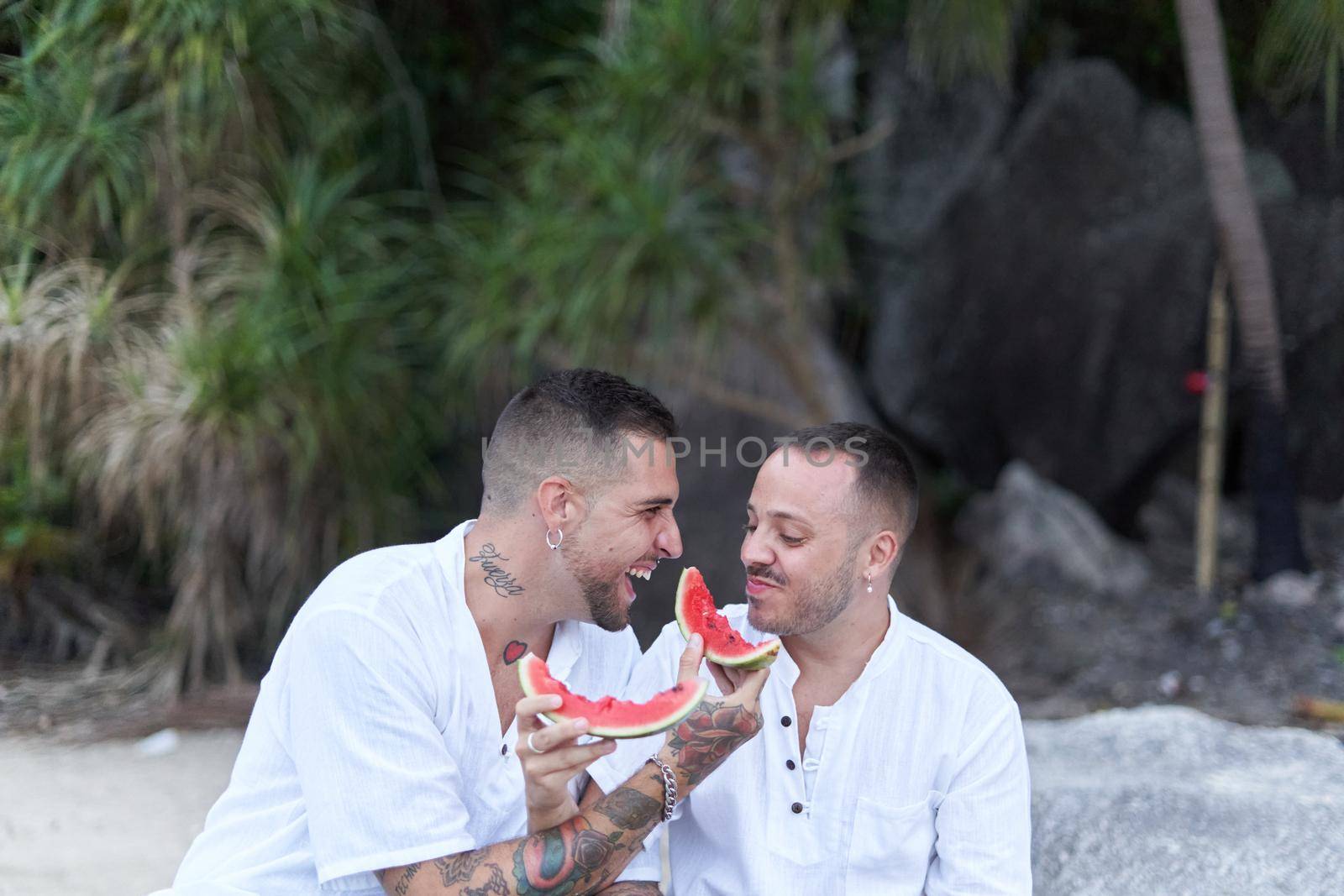 Gay couple laughing while feeding each other with watermelon outdoors by WesternExoticStockers