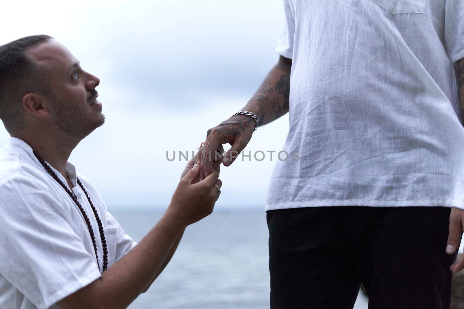Homosexual man with an emotional face asking to marry him to his gay partner on a beach