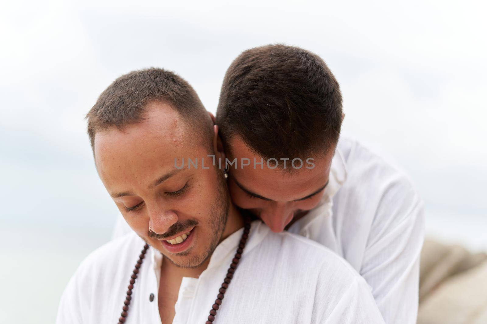 Close up photo of a homosexual couple in love embracing tenderness on a beach