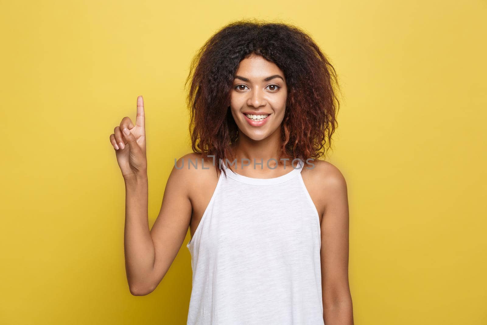Beautiful attractive African American woman with curly afro hair thinking of something. Yellow studio background. Copy Space. by Benzoix