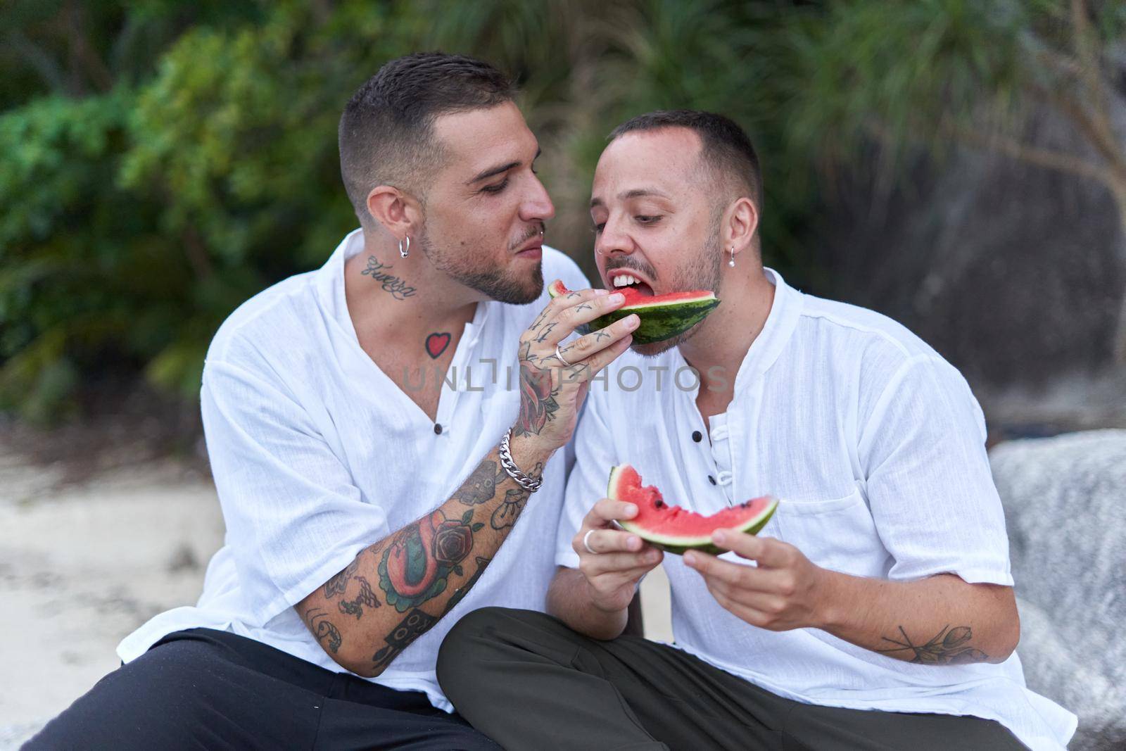 gay couple sharing a slice of watermelon on a tropical beach by WesternExoticStockers