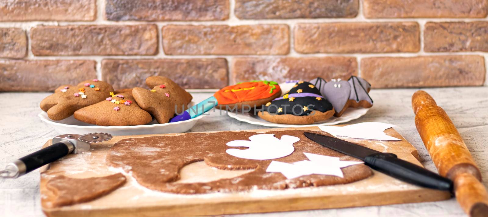 banner with making homemade gingerbread cookies for Halloween on brick wall background.Preparation for Halloween.Funny gingerbread.Halloween gingerbread. Cutting out gingerbread Halloween. Soft focus