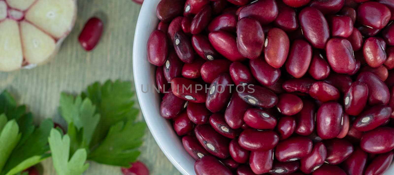 banner with close-up of red beans in a white cup with spices on a wooden table. top view
