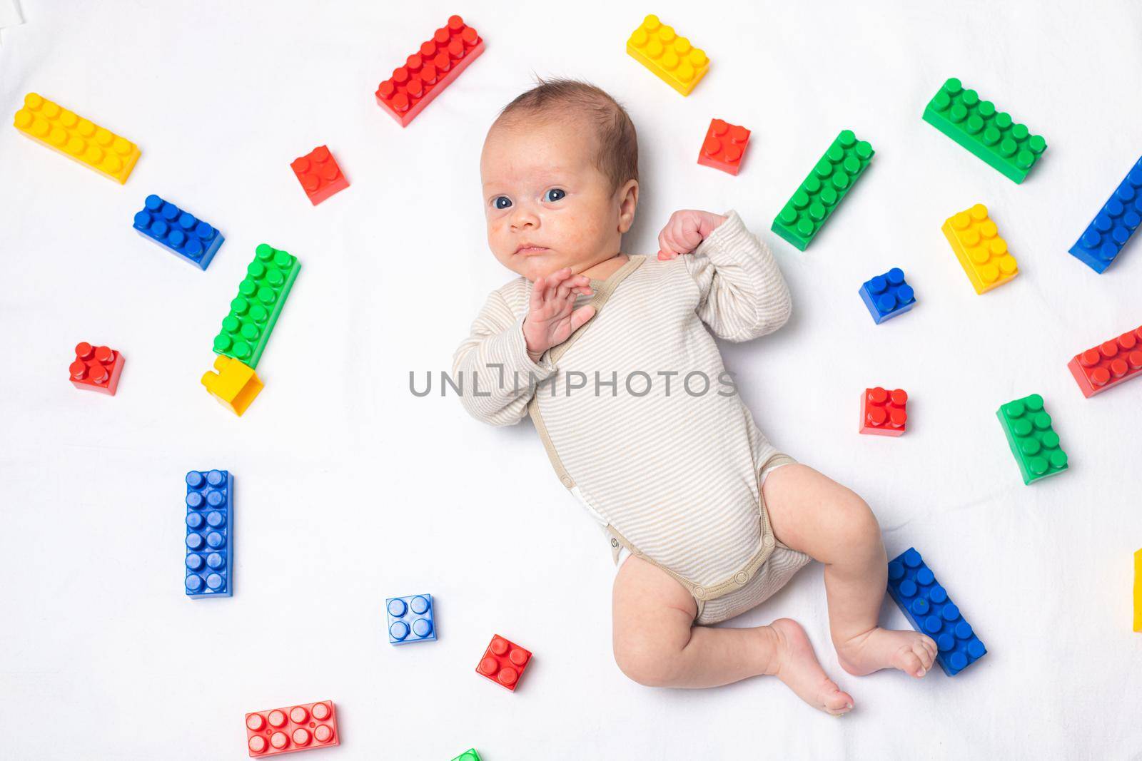 The baby is lying in toys . An article about children's toys. A selection of toys for kids. Designer