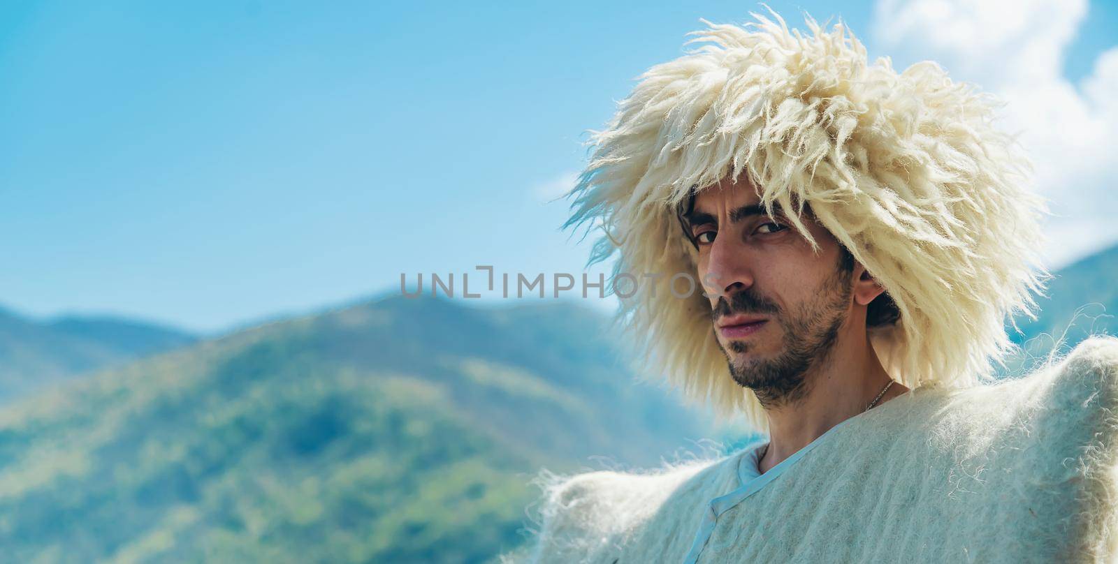 A Georgian man in a hat against the background of mountains and the sky. Selective focus. People.