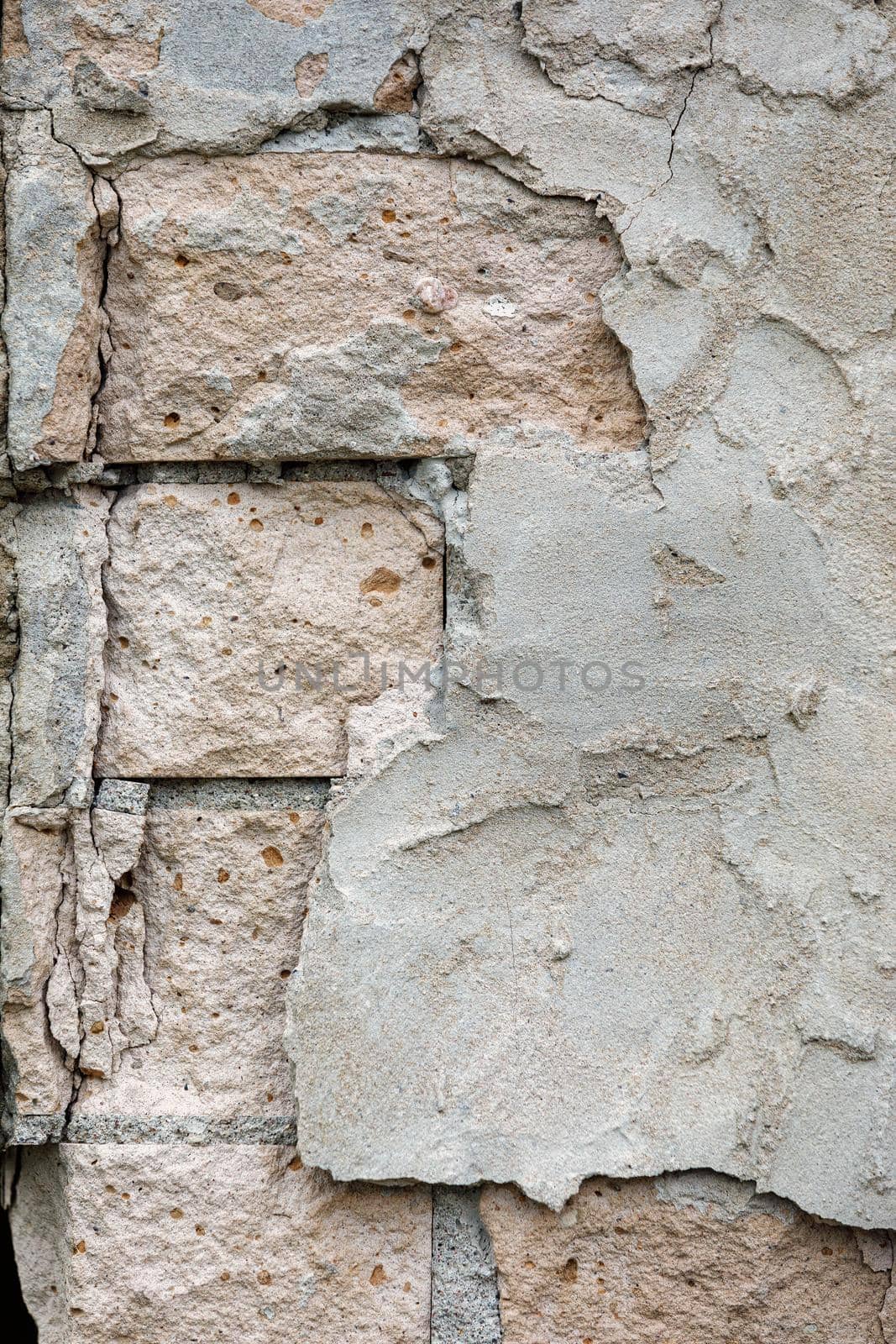 White brick plastered wall crumbling plaster, visible white and part of the old bricks. Crumbling brick wall with cracks