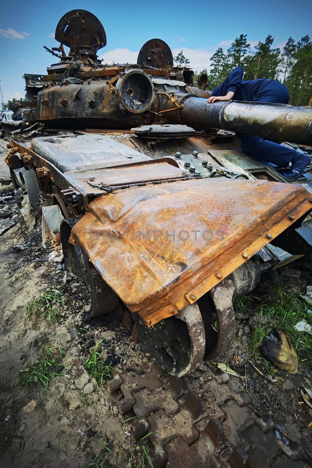 Kyiv region, Ukraine - May 15, 2022: War in Ukraine. Highway Kyiv - Zhytomyr. People take selfies against destroyed russian tank after russian atack in Febrary