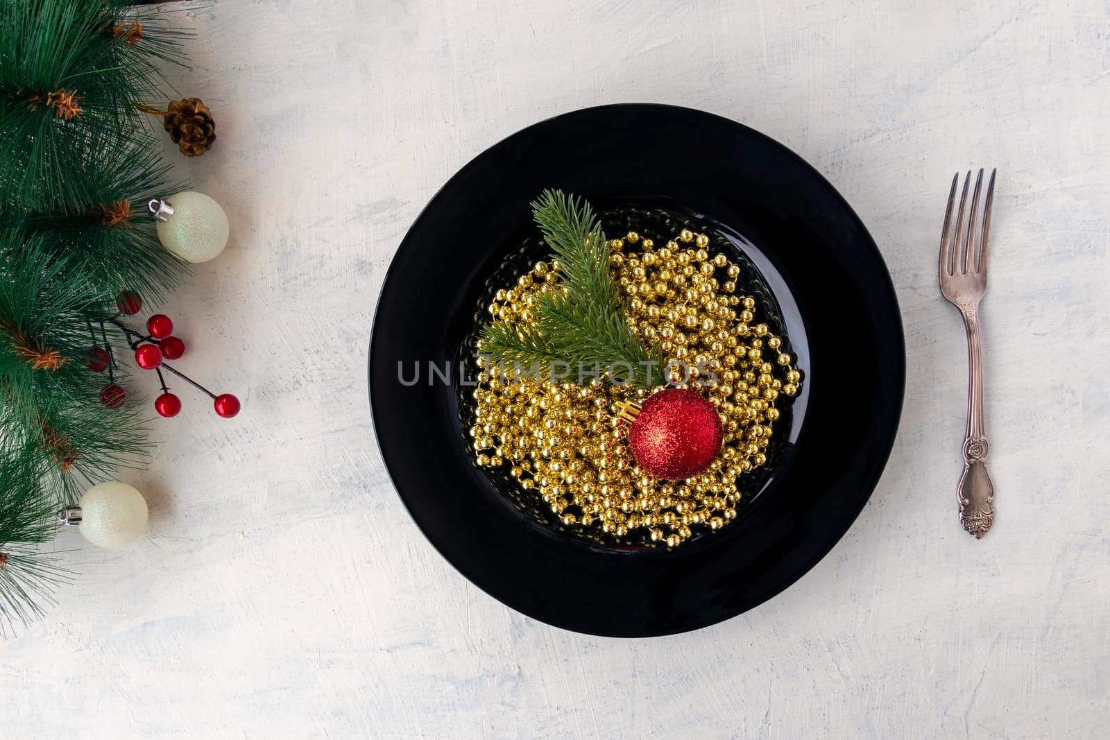 flat lay Christmas decorations, golden beads, branches of a Christmas tree and a red Christmas ball in a black plate, like Italian pasta. festive food concept for christmas or new year. by Leoschka