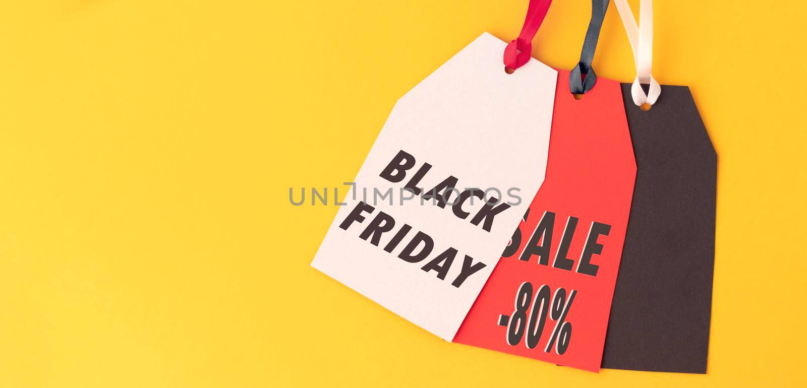 banner with three paper labels with the text black Friday sale written in it against a yellow background. Black Friday concept. by Leoschka