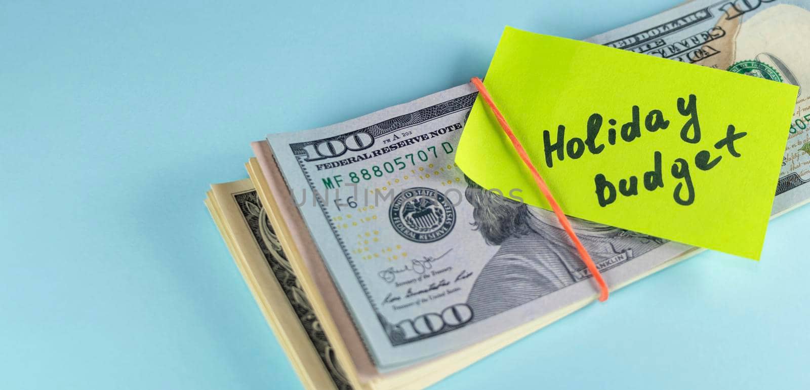 banner with text written note Holiday budget, dollars cash money in rubber band with note, on background - concept of financial planning of set budget for Christmas or holiday