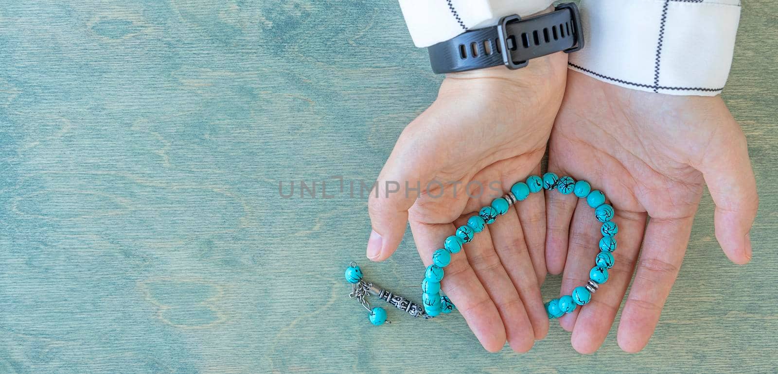 banner with top view on female hands holding rosary beads. Ramadan Kareem background. Muslim woman in white clothes holds a rosary. Flat lay. copy space