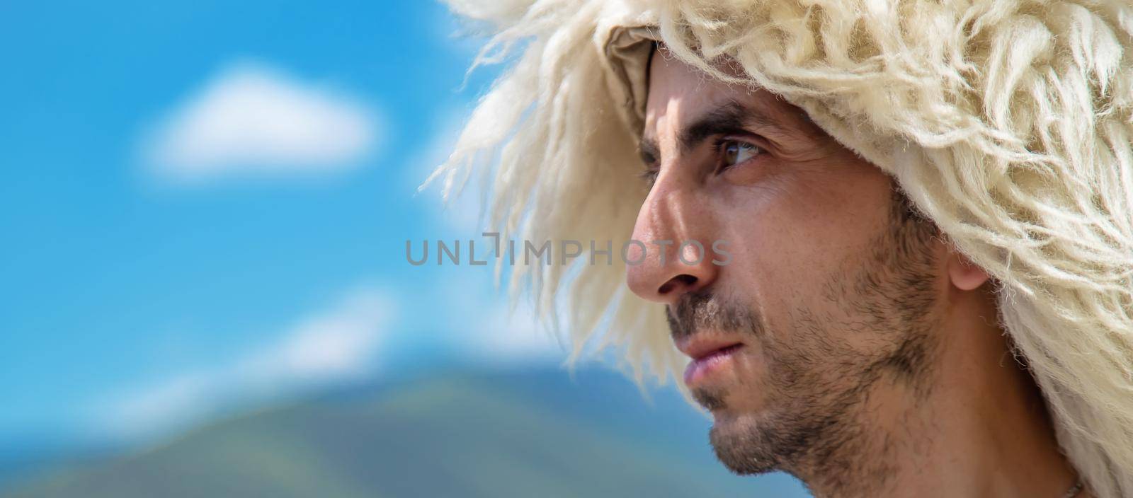 A Georgian man in a hat against the background of mountains and the sky. Selective focus. People.