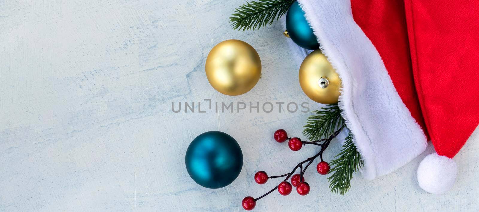 banner with Christmas balls in Santa Claus hat with branches of Christmas tree and on a white concrete table. Concept Merry Christmas and Happy New year. Copy space. Flat lay.