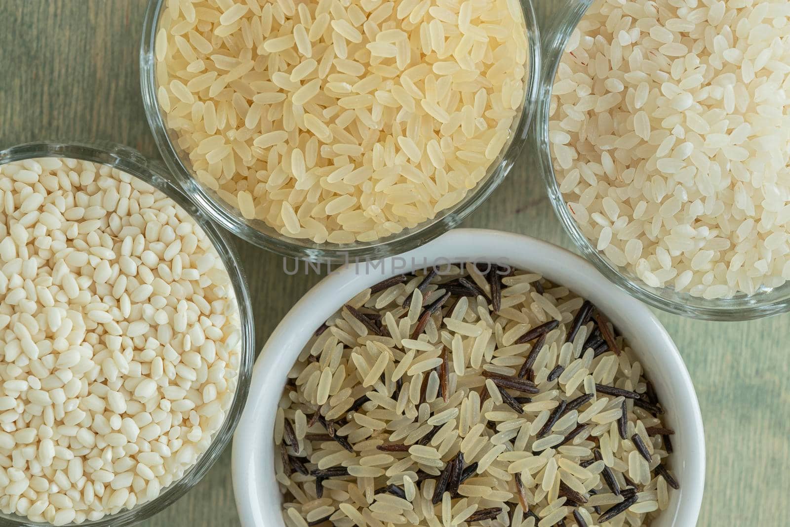 Flat lay of close up variety of rice in different cups on a wooden table. the concept of selection and correct selection of rice for cooking. by Leoschka