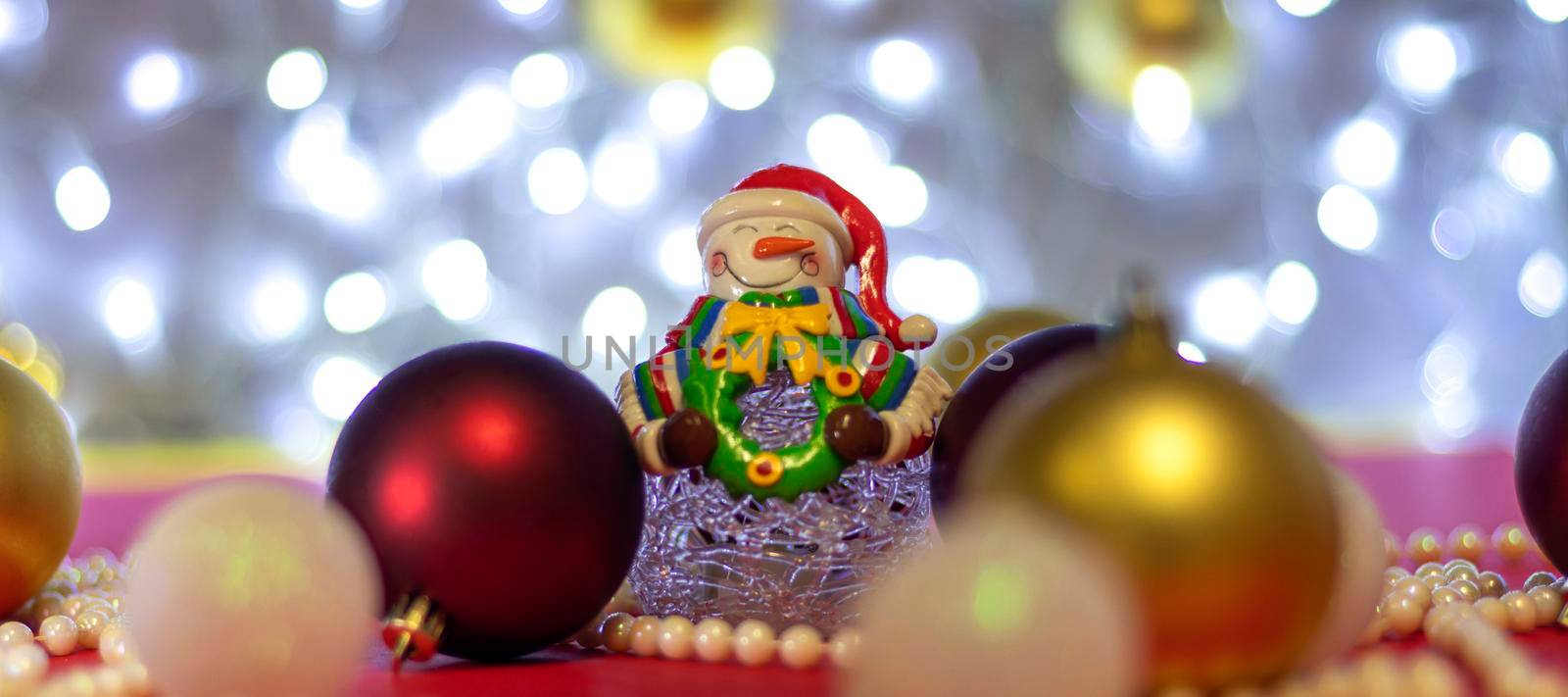 banner with Snowman with blur Christmas balls and Christmas beads on bokeh background. Christmas background or Christmas card. New Year or Xmas concept. Copy spase