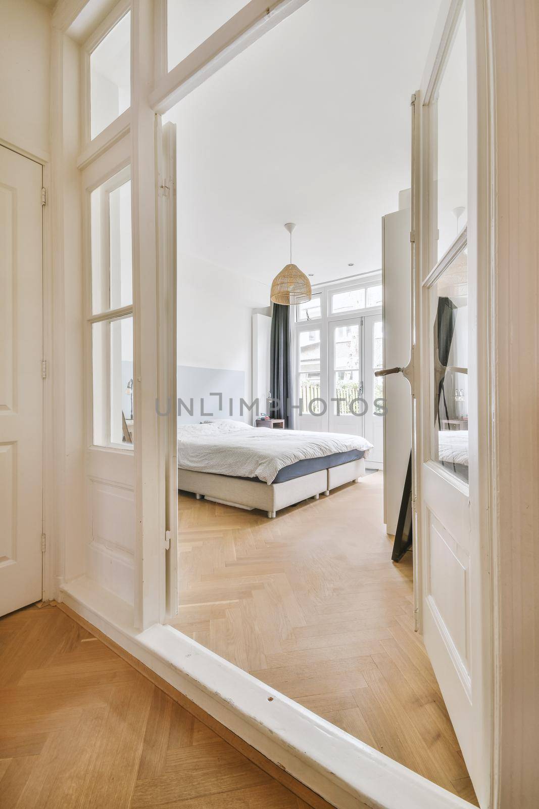 Entrance to a spacious bedroom with a large bed and access to the backyard of a modern house