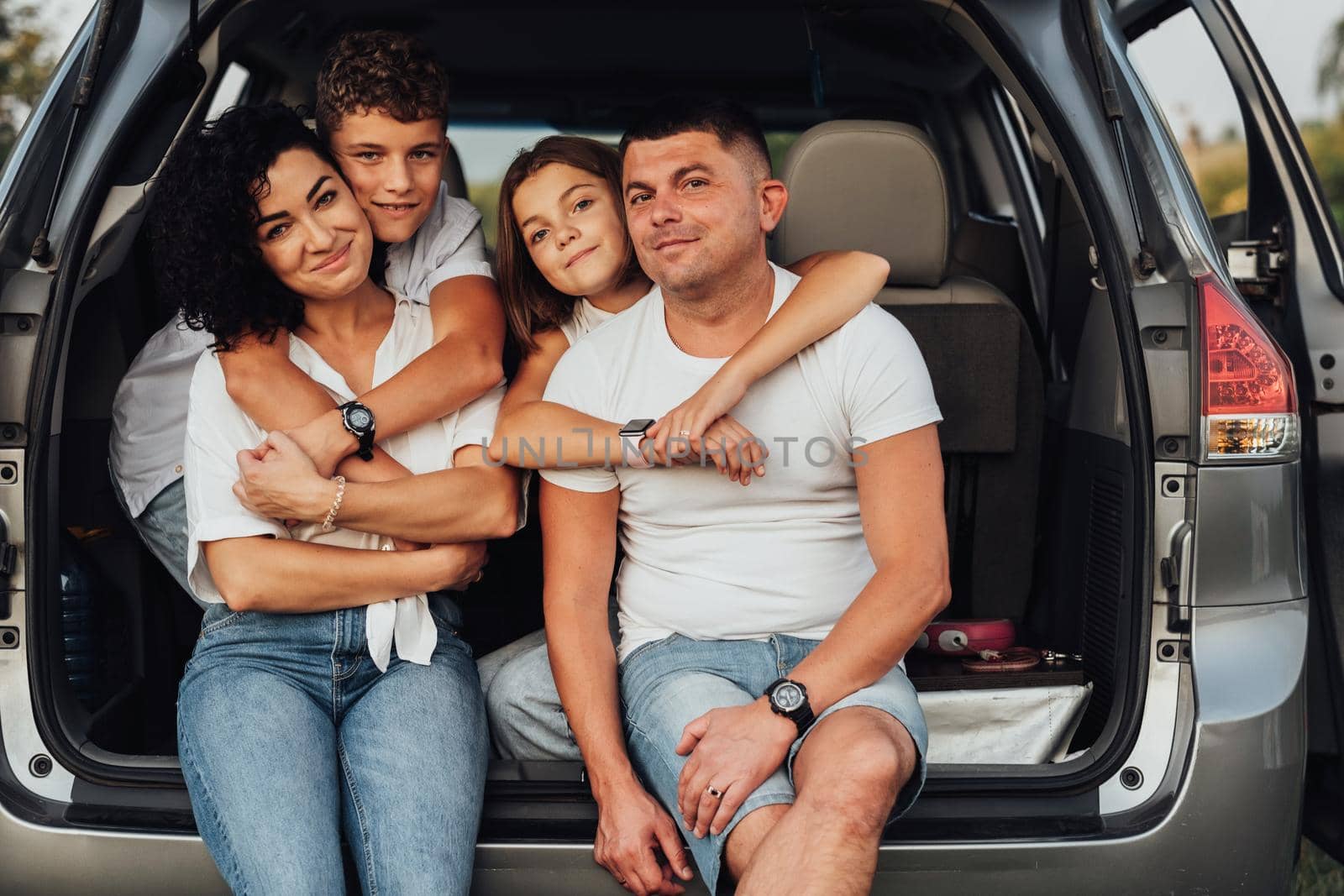 Portrait of Happy Four Caucasian Members Family Sitting in Trunk of Minivan Car, Mother and Father with Two Teenage Children, Son and Daughter Having Weekend Outdoors