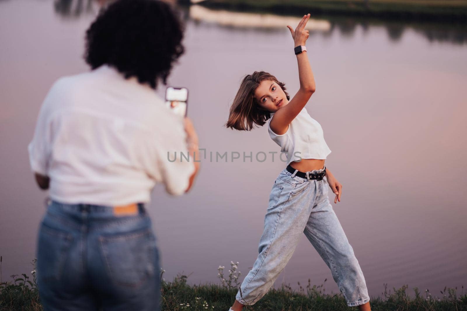 Mother Taking Picture of Her Teenage Daughter on Smartphone for Social Network Outdoors by Lake