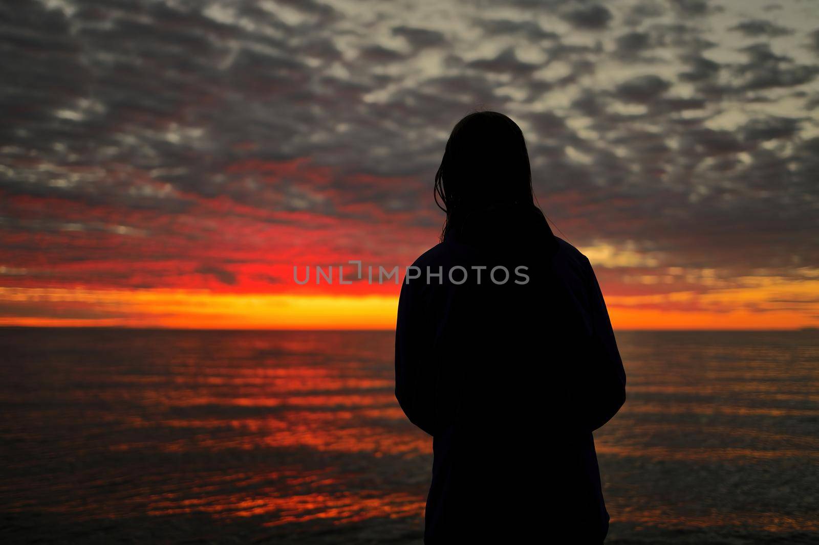 A Young Adolescent Girl Looks in Awe, Wonder, and Admiration at a Magnificent Sunset Sky by markvandam