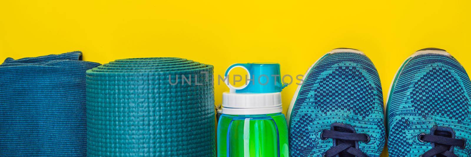 BANNER, LONG FORMAT Everything for sports turquoise, blue shades on a yellow background. Yoga mat, sport shoes sportswear and bottle of water. Concept healthy lifestyle, sport and diet. Sport equipment. Copy space by galitskaya