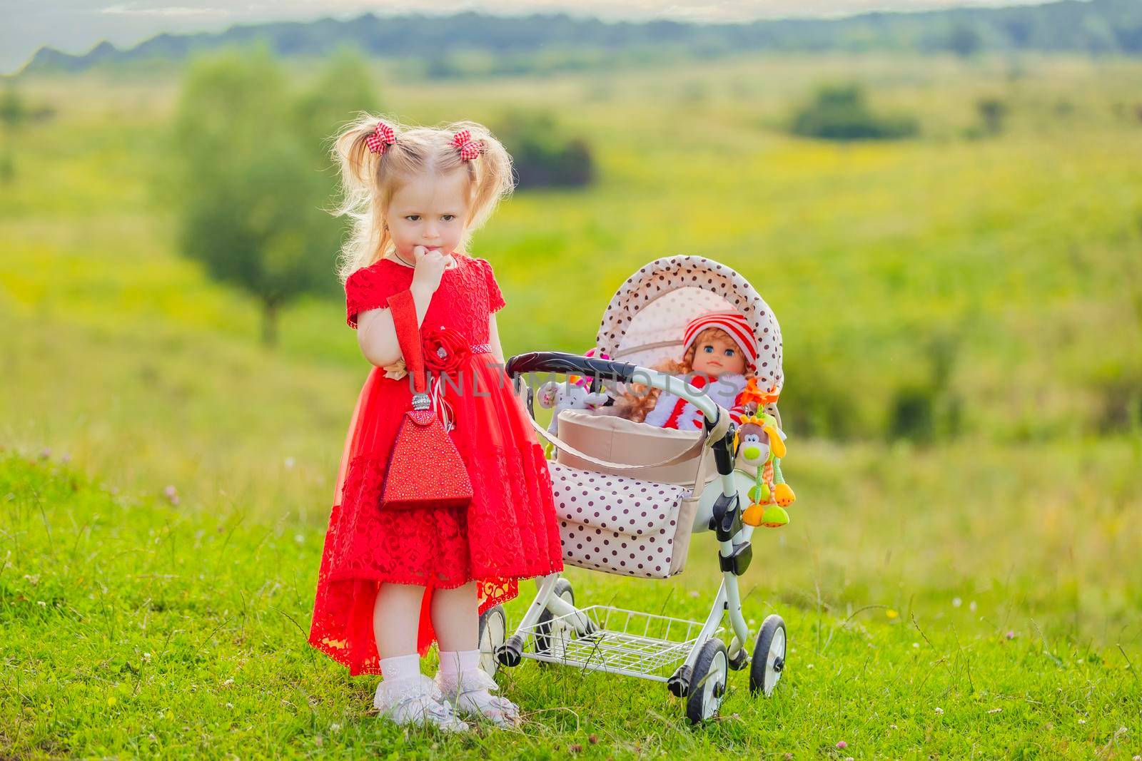 girl with a toy stroller walks in nature