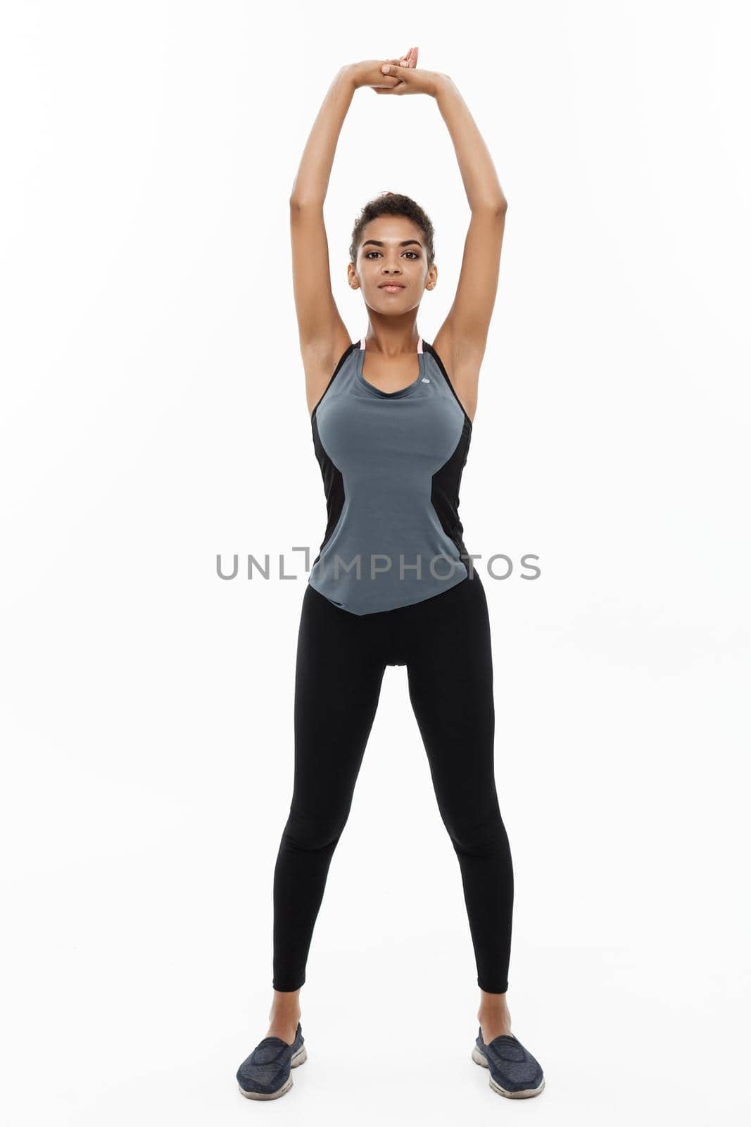 Sport, training, lifestyle and Fitness concept - Full-length portrait of beautiful happy African American woman stretching hands. Isolated on white studio background