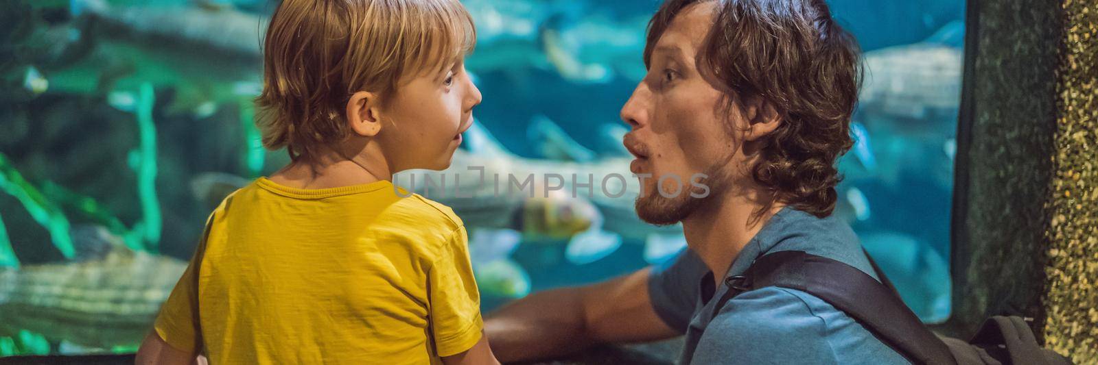 Father and son looking at fish in a tunnel aquarium. BANNER, LONG FORMAT