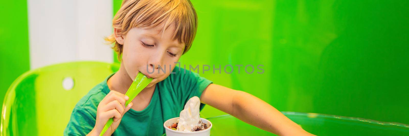 Happy young boy eating a tasty ice cream or frozen yogurt BANNER, LONG FORMAT by galitskaya