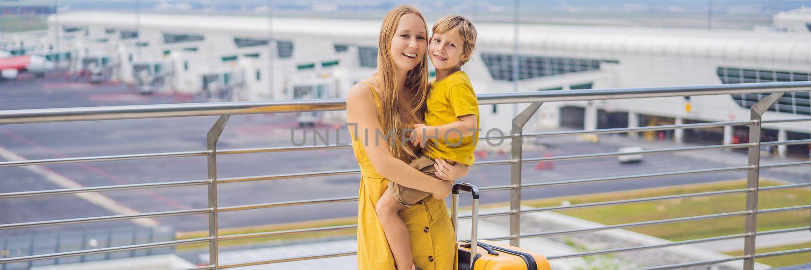 BANNER, LONG FORMAT Family at airport before flight. Mother and son waiting to board at departure gate of modern international terminal. Traveling and flying with children. Mom with kid boarding airplane. yellow family look.