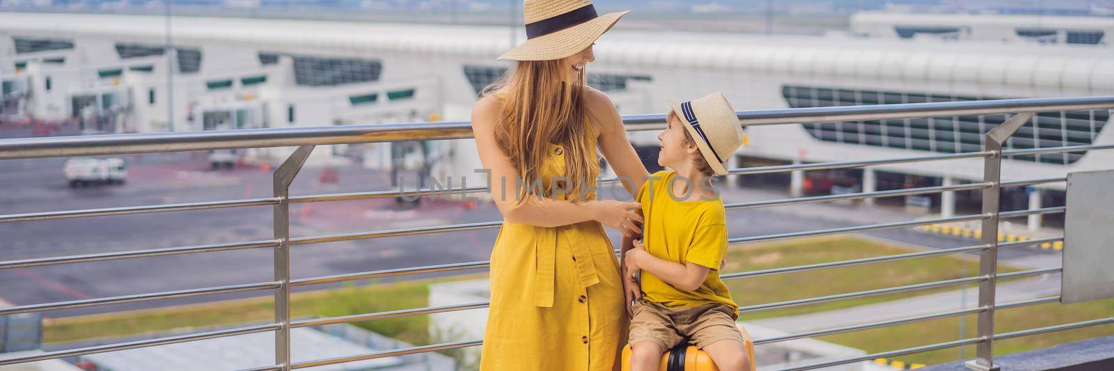 BANNER, LONG FORMAT Family at airport before flight. Mother and son waiting to board at departure gate of modern international terminal. Traveling and flying with children. Mom with kid boarding airplane. yellow family look.