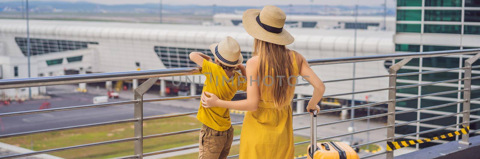 BANNER, LONG FORMAT Family at airport before flight. Mother and son waiting to board at departure gate of modern international terminal. Traveling and flying with children. Mom with kid boarding airplane. yellow family look.
