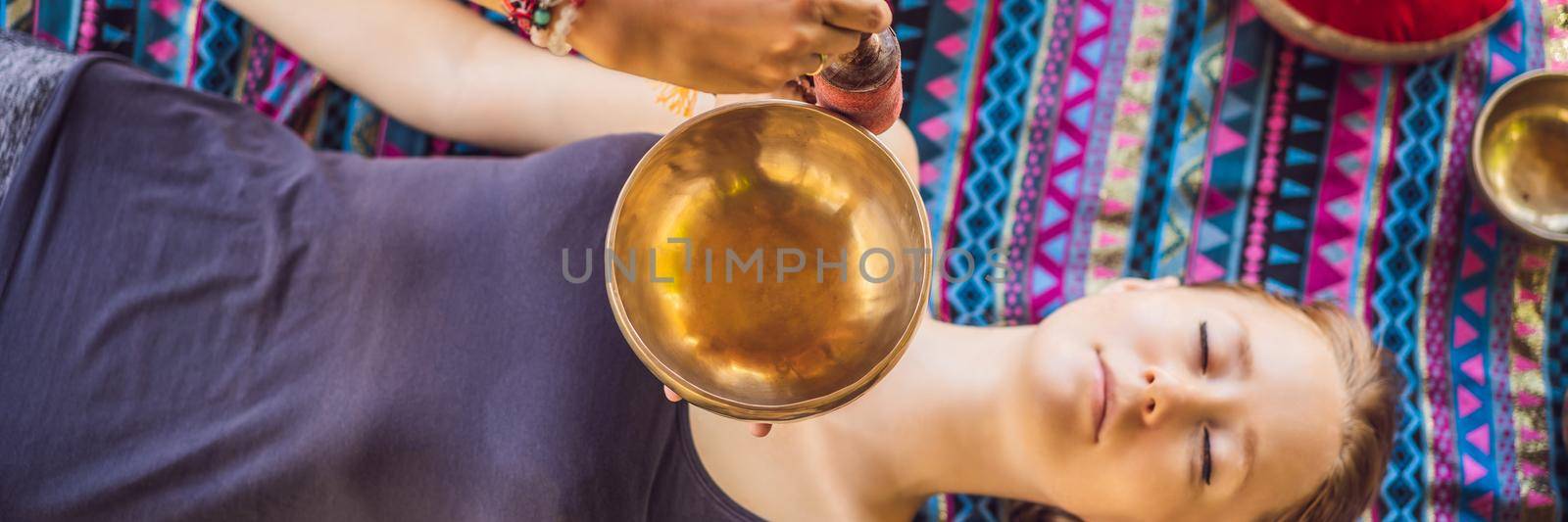 BANNER, LONG FORMAT Nepal Buddha copper singing bowl at spa salon. Young beautiful woman doing massage therapy singing bowls in the Spa against a waterfall. Sound therapy, recreation, meditation, healthy lifestyle and body care concept.