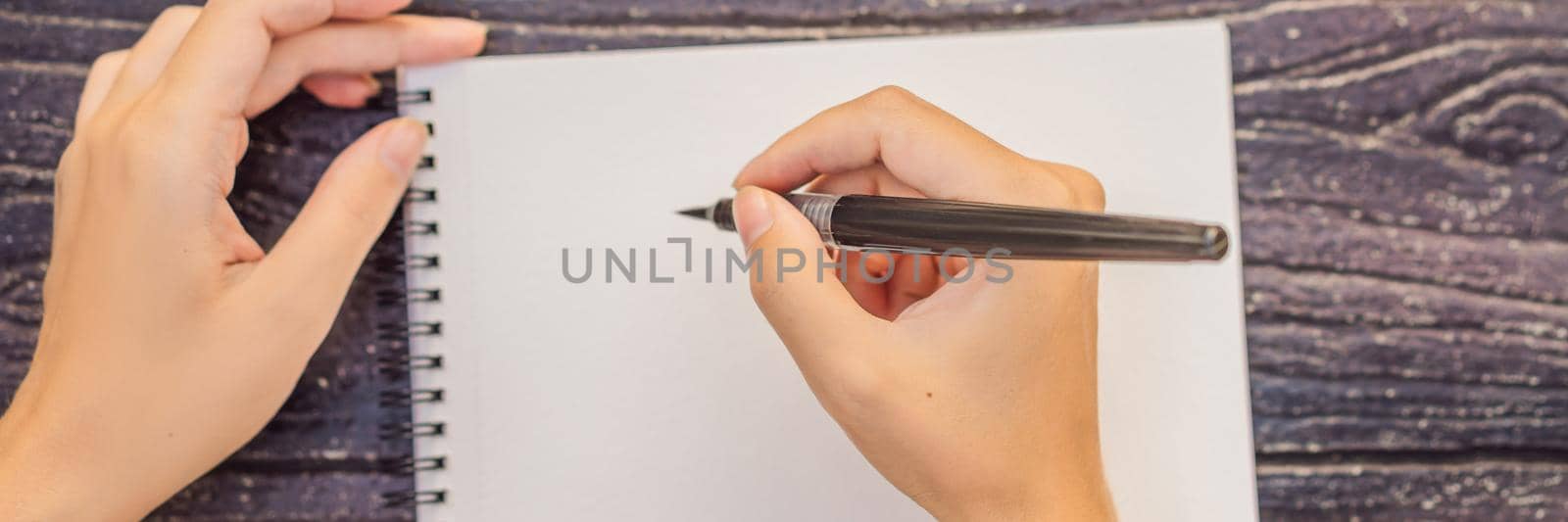 Women's hands in a wooden background holding a signboard, drawing block, paper, mockup. BANNER, LONG FORMAT