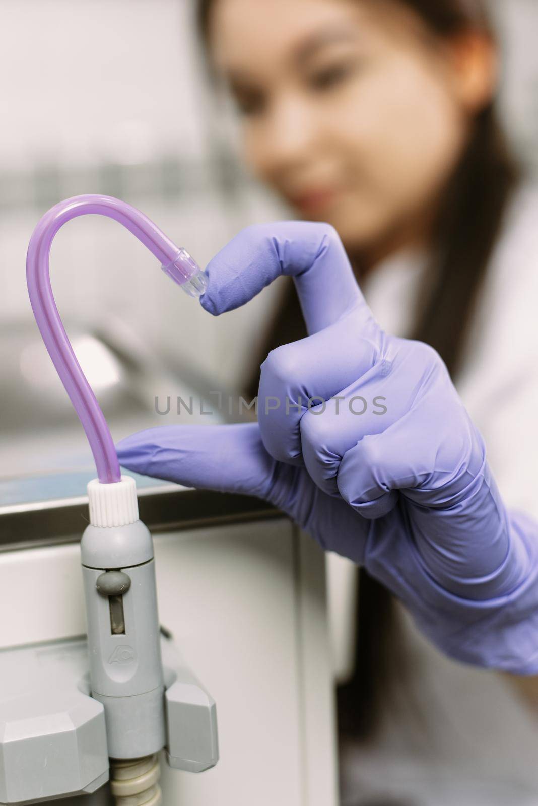 Hand in Blue latex glove and saliva ejector symbolize love in dentistry. Heart symbol. Dental treatment, healthcare and dentistry concept.