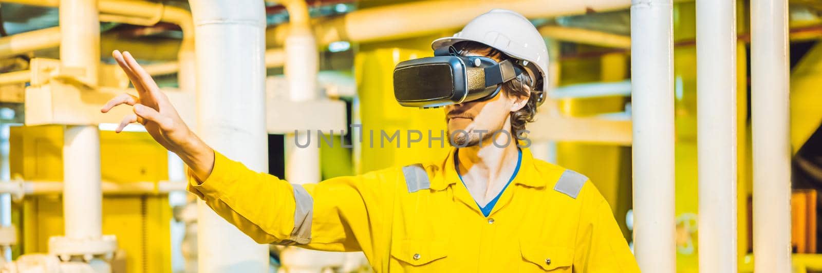 BANNER, LONG FORMAT Young woman in a yellow work uniform, glasses and helmet uses virtual reality glasses in industrial environment,oil Platform or liquefied gas plant.