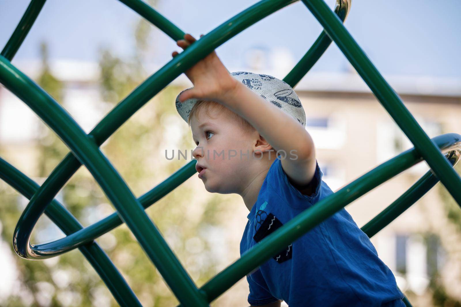 Little boy very focused climb on the green tube ladders in playground.