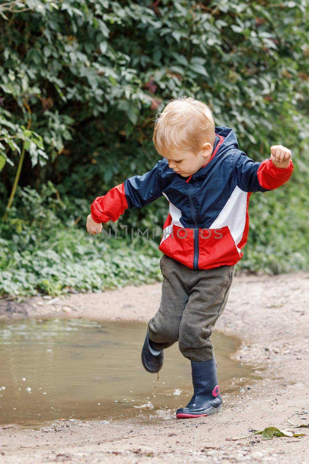 Young children playing in a muddy puddle.