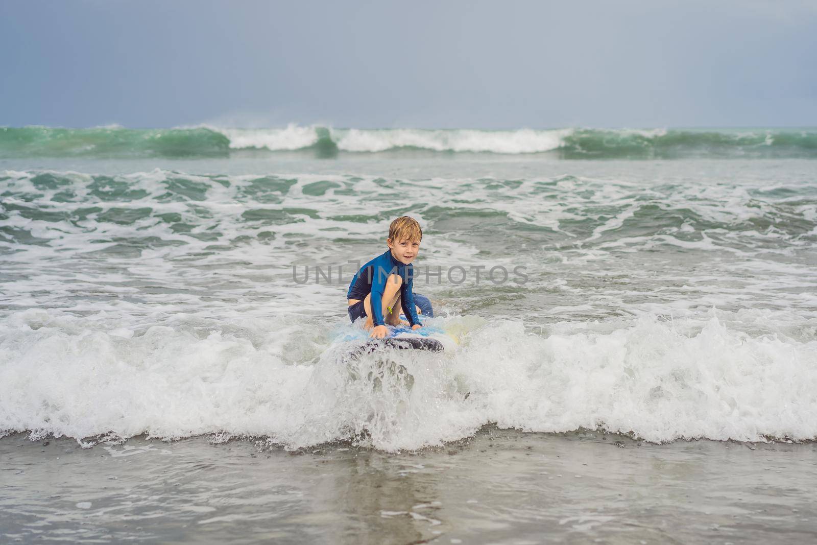 Father or instructor teaching his 5 year old son how to surf in the sea on vacation or holiday. Travel and sports with children concept. Surfing lesson for kids by galitskaya