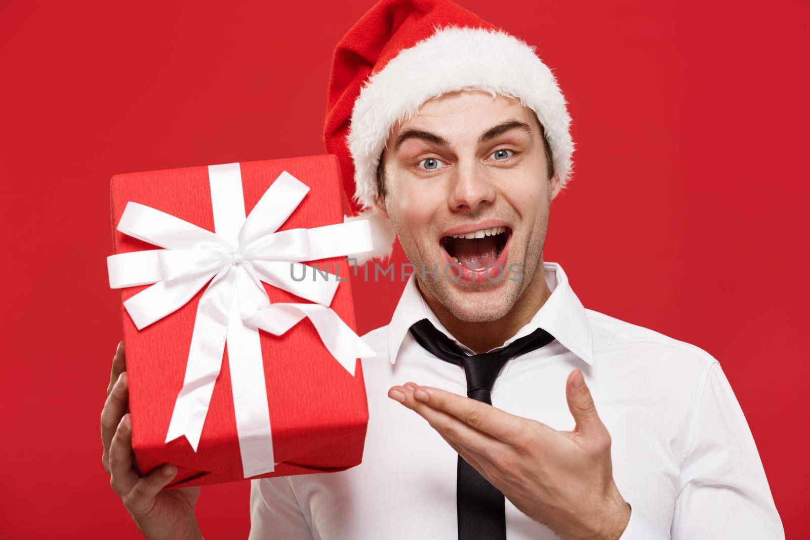 Christmas Concept - portrait close-up Santa christmas businessman over red background holding red gift. by Benzoix