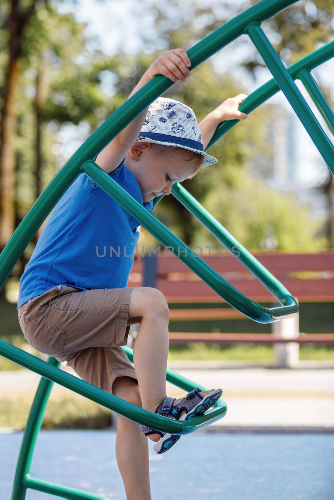 Little boy very focused climb on the tube ladders in city playground.