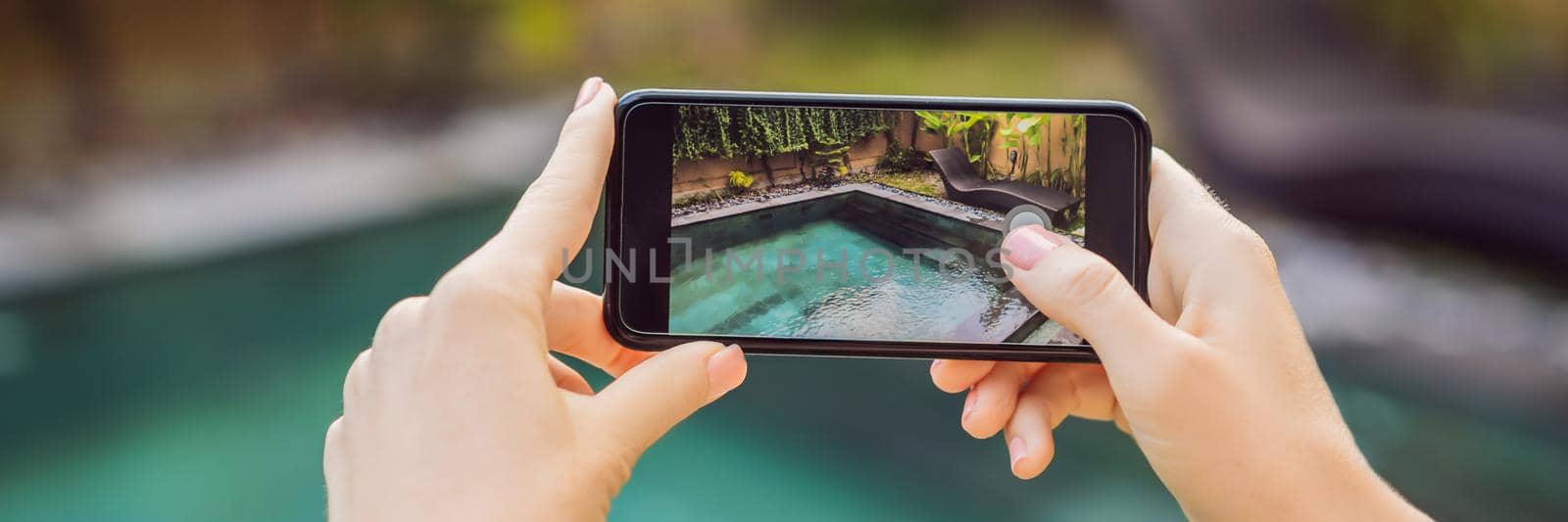 hand holding phone on background of the pool in hotel. photo camera on the screen. close up hand hold smartphone take a picture of summer vacation BANNER, LONG FORMAT by galitskaya