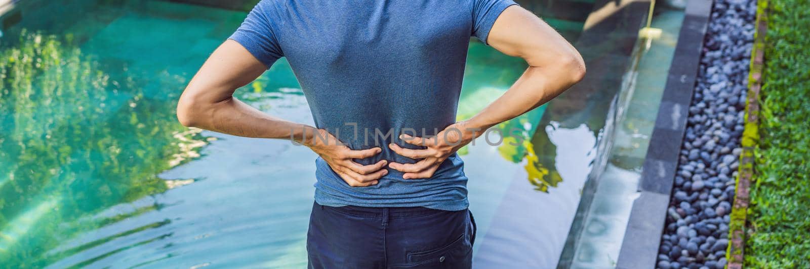 Men's back hurts against the backdrop of the pool. Pool helps with back pain. BANNER, LONG FORMAT